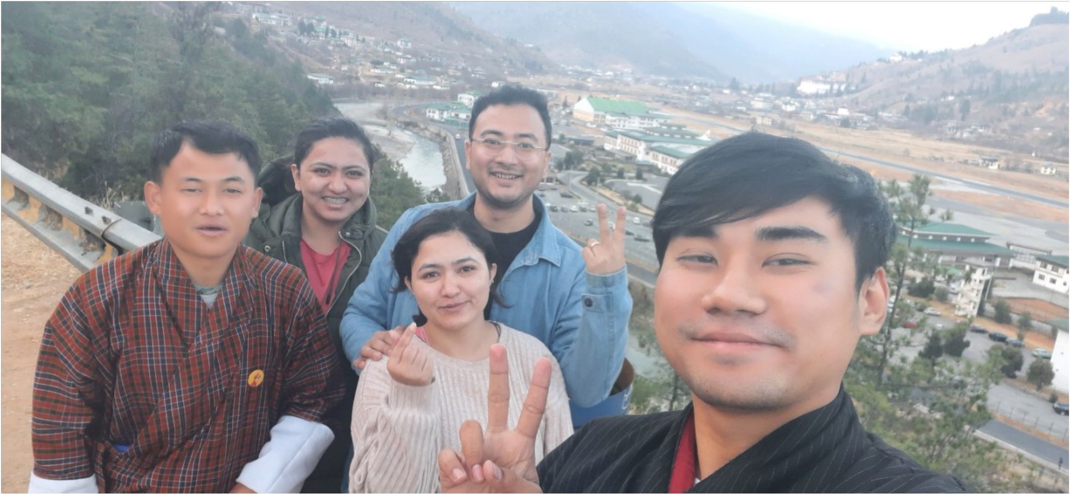 Group selfie of travelers above a Bhutanese valley town