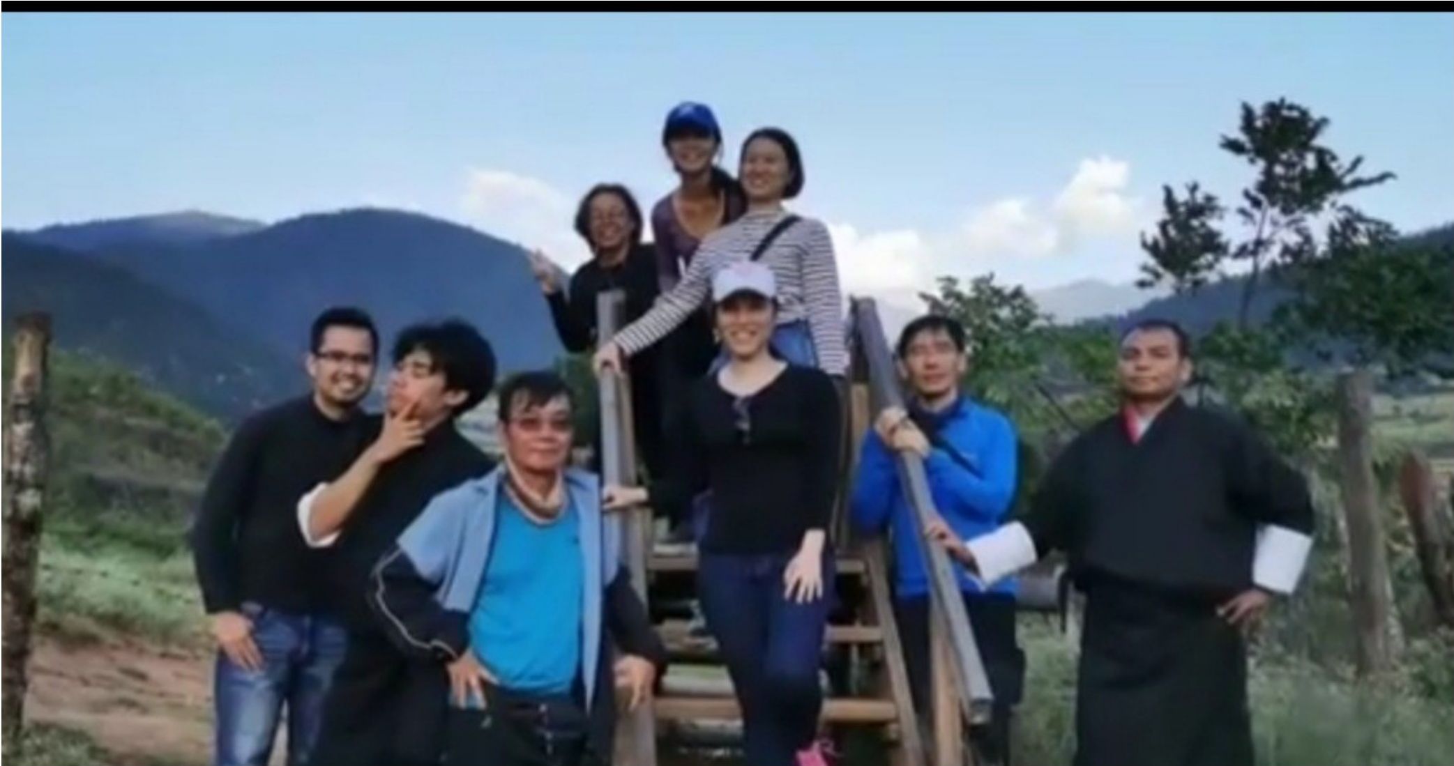 Travelers posing on a wooden staircase in the Bhutanese mountains